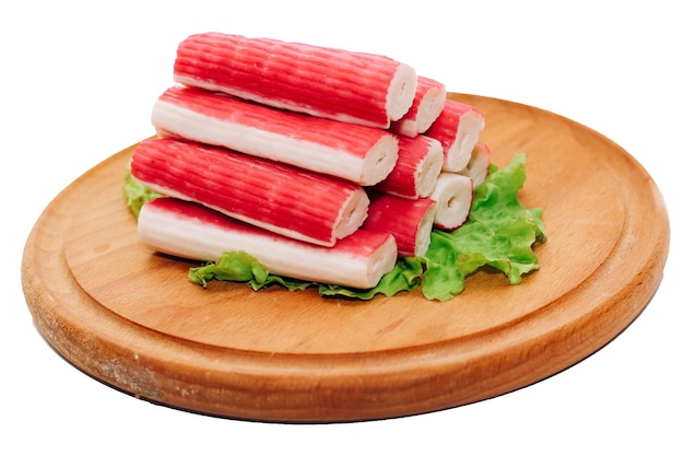 Bâtonnets de crabe rouleaux de surimi pliés en pyramide avec concombre et maïs sur une planche de bois isolée sur fond blanc