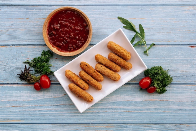 Bâtonnets de fromage mozzarella croustillants frits avec sauce tomate isolés sur la vue de dessus de table en bois