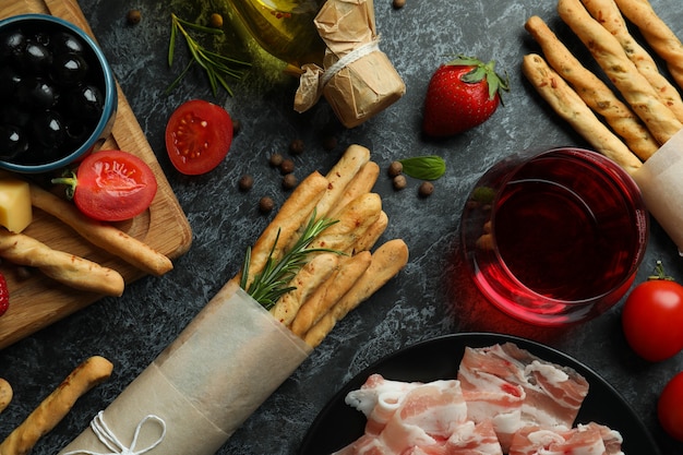 Bâtonnets de Grissini, collations et vin sur une surface fumée noire