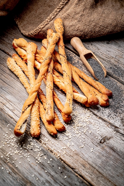 Bâtonnets de pain sur un fond en bois, avec du fromage, des graines de sésame et des graines de pavot.