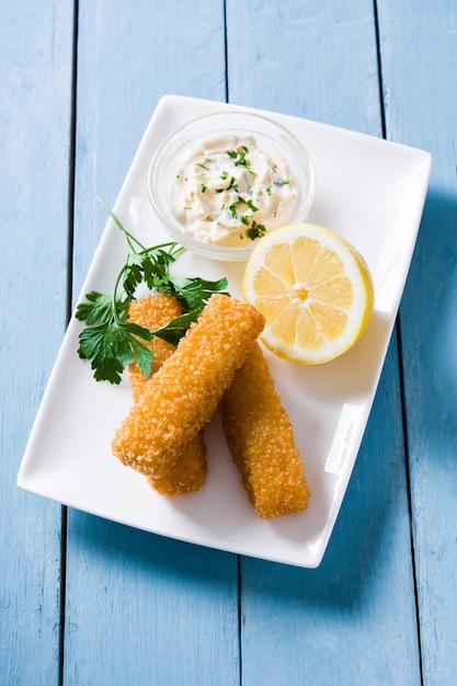 Bâtonnets de poisson frit croustillant au citron et sauce sur bois bleu, vue du dessus