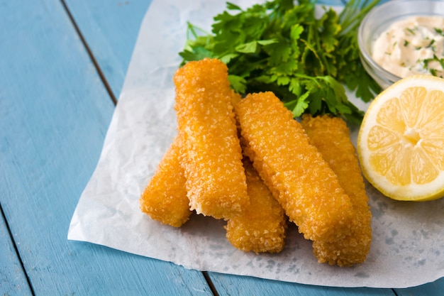 Bâtonnets de poisson frits croustillants au citron et sauce sur bois bleu