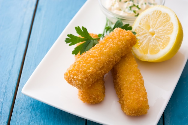 Bâtonnets de poisson frits croustillants au citron et sauce sur bois bleu