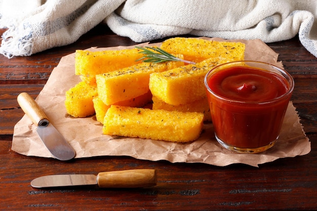 Bâtonnets de polenta frits dans du papier sur une table en bois rustique