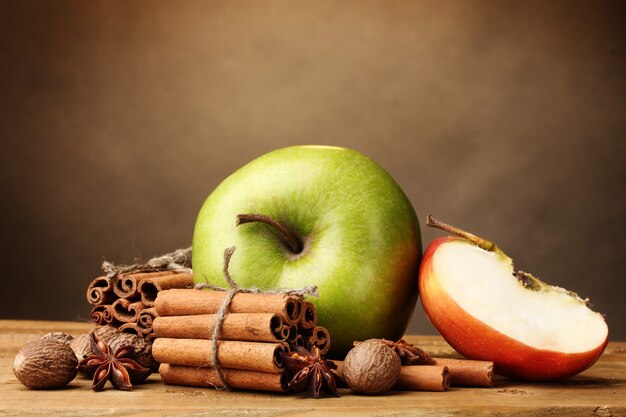 Bâtons de cannelle, pomme muscade et anis sur table en bois sur fond marron