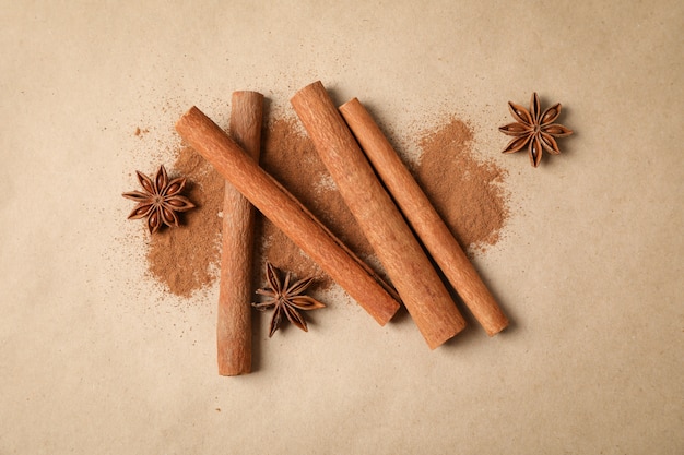 Bâtons de cannelle, poudre et étoiles d'anis sur mur beige ou en carton, vue de dessus