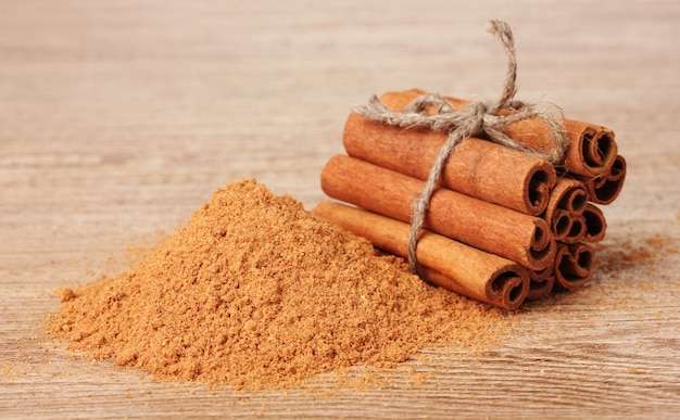 Bâtons de cannelle et poudre sur table en bois