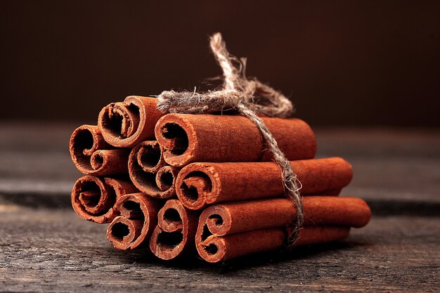 Bâtons de cannelle sur table en bois sur fond marron