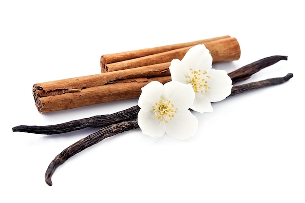 Photo bâtons de vanille et cannelle avec des fleurs sur blanc