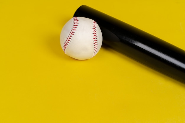 Batte de baseball et balle sur fond jaune vif