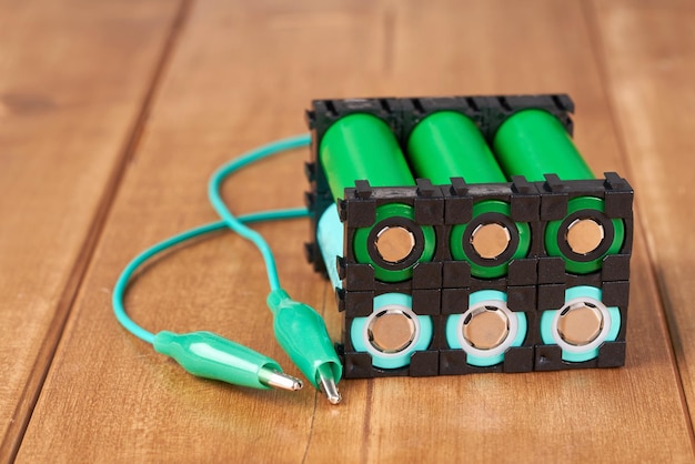 Batterie au lithium dans un support en plastique noir sur une table en bois.