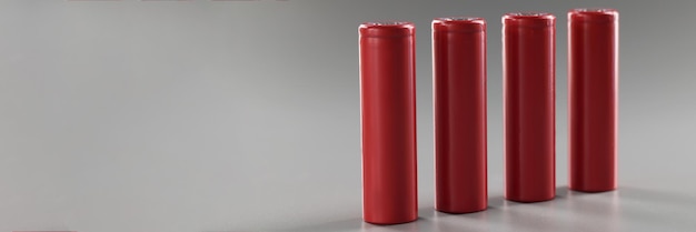 Les batteries en alliage rouge se tiennent dans une rangée sur un fond gris