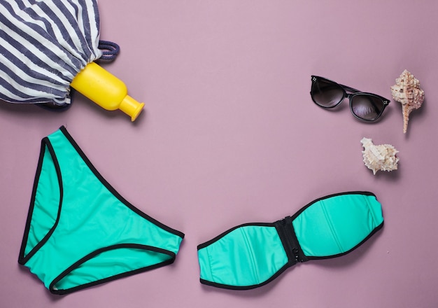 Beachwear et accessoires d'été sur rose. Maillot de bain femme, lunettes de soleil, sac de plage