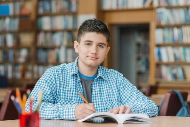 Beau adolescent prendre des notes dans le manuel