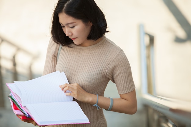 Beau, asiatique, femme, collège, regarder, elle, livre, debout, dehors