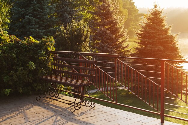 Beau banc ajouré à l'aube sur la rive du lac en été