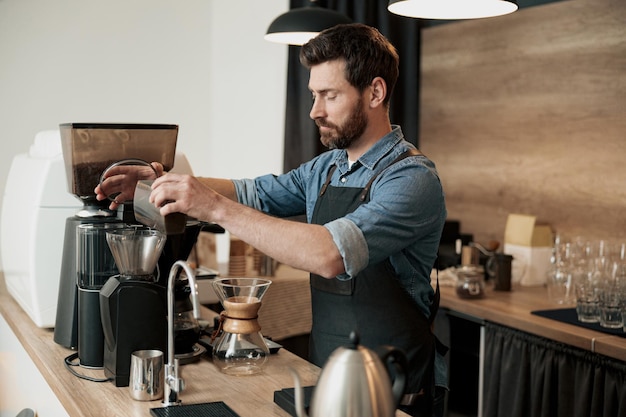 Un Beau Barista Broie Des Grains De Café Dans Une Machine à Café