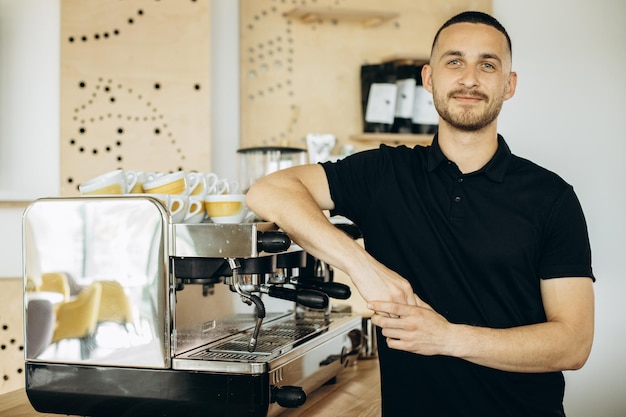 Beau barista debout près de la machine à café au café