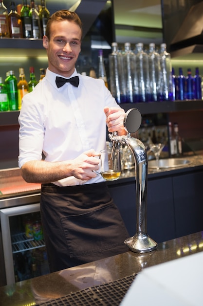 Beau barman tirant une pinte de bière