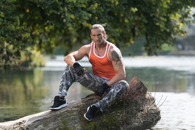 Beau beau et attrayant homme adulte avec un corps musclé se détendre à l'extérieur dans la nature