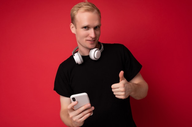 Beau beau jeune homme blond portant un t-shirt noir et un casque blanc debout