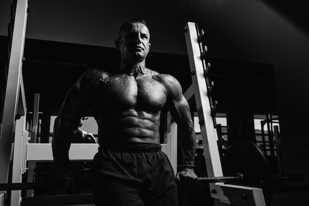 Beau beau et séduisant homme mûr avec un corps musclé relaxant dans la salle de sport