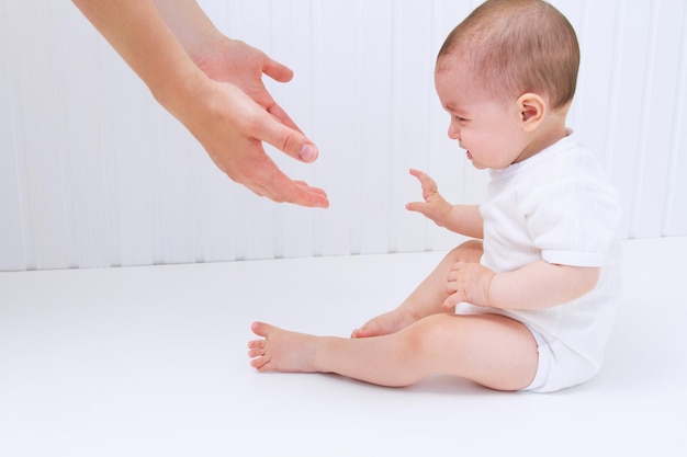 Beau bébé avec l'aide des mains de la mère sur fond blanc