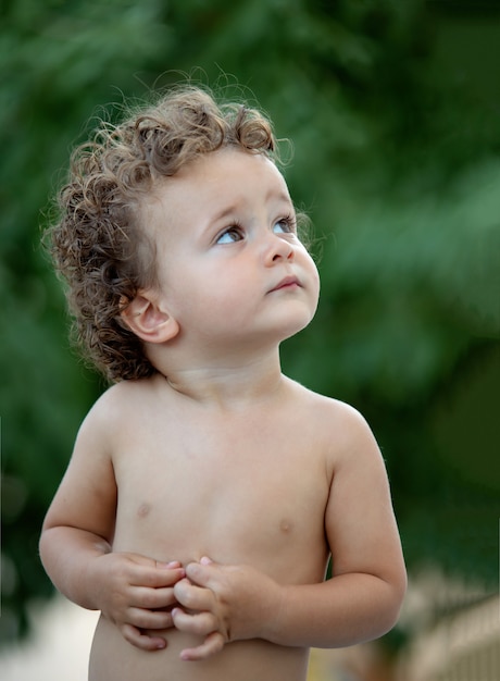 Beau bébé aux cheveux bouclés dans le jardin