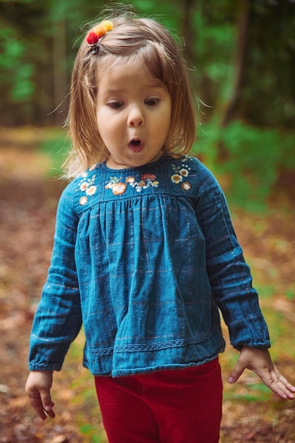 beau bébé dans une chemise brodée joue dans la forêt