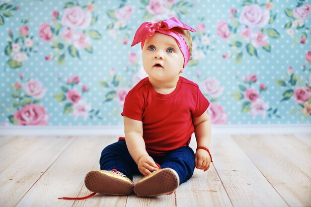 Beau bébé dans une veste rose et un jean assis sur le sol. la parentalité.