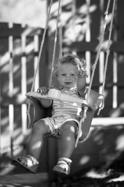 Beau bébé garçon avec swing d'enfant posant photographe pour le cadre de photo en couleur composé de bébé garçon with swing d'enfants expression caucasienne visage bébé garçon en bonne santé sur swing d'enfance relaxant pour la prise de vue