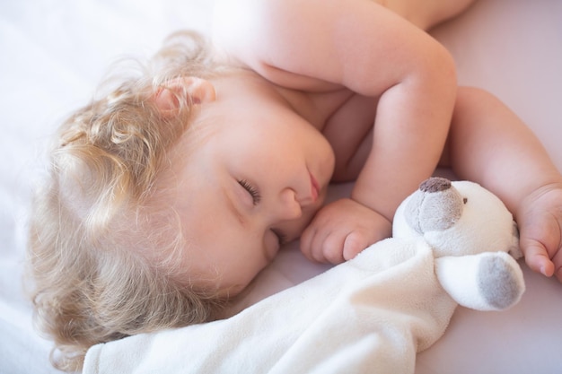 Beau bébé mignon dormant dans son lit à la maison avec un enfant jouet dormant dans le lit