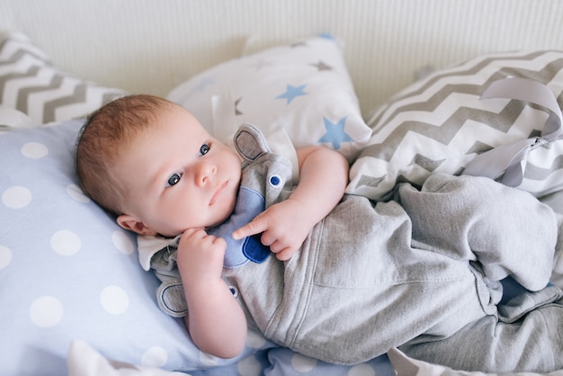 Beau bébé nouveau-né couché dans des oreillers dans des tons délicats de gris, bleu, blanc