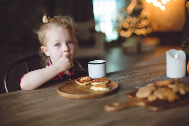 Un beau bébé prend son petit déjeuner avec des crêpes.