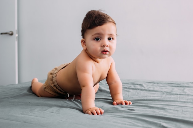 Beau bébé rampant sur le lit dans la chambre, mode de vie familial