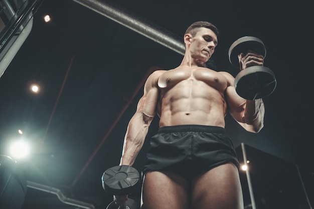 Beau bodybuilder puissant au gymnase