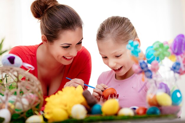 Beau bonheur mère et fille peignant l'oeuf de Pâques à la maison.