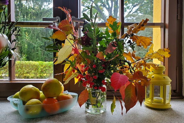 Photo beau bouquet d'automne sur le rebord de la fenêtre, fleurs, feuilles, baies, blocs. photo de haute qualité