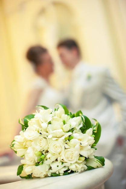 Beau bouquet blanc de fleurs sur le fond d'une silhouette floue d'un couple d'amoureux