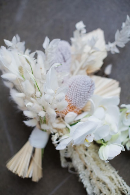 Beau bouquet boho de mariage avec des orchidées banksia et des fleurs sèches sur un fond de béton gris