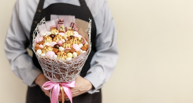 Beau bouquet de bonbons, guimauves et biscuits entre les mains d'un confiseur