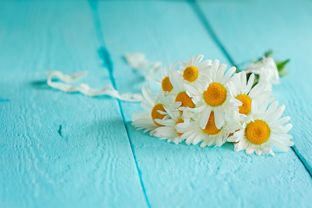 Beau bouquet de camomille sur une table en bois bleue.