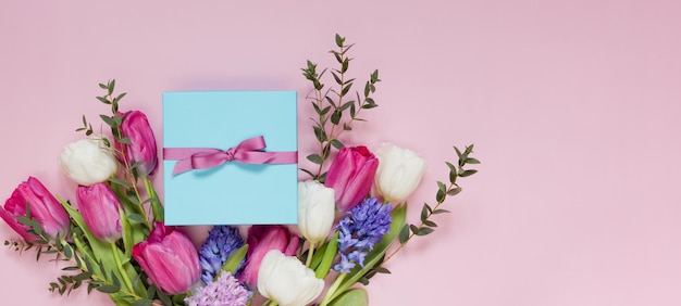 Beau bouquet et coffret cadeau bleu avec ruban sur fond rose Concept de vacances 8 mars