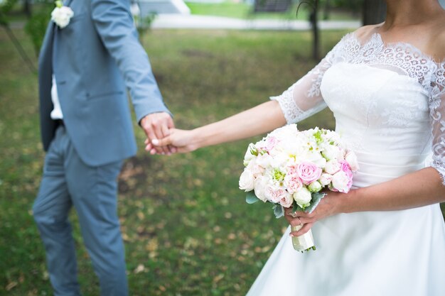 Beau bouquet coloré de mariage avec différentes fleurs dans les mains de la mariée. Bouquet de mariée d'été