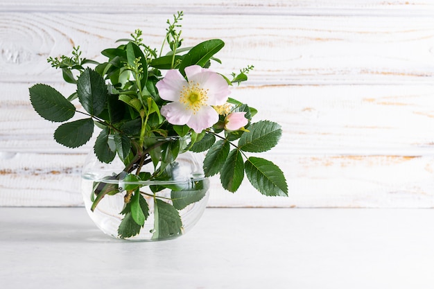 Beau bouquet d'été avec rose sauvage sur fond en bois blanc.