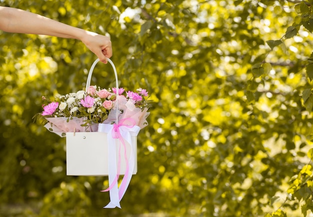 Un beau bouquet de fleurs dans une boîte entre les mains d'une belle fille sur fond vert