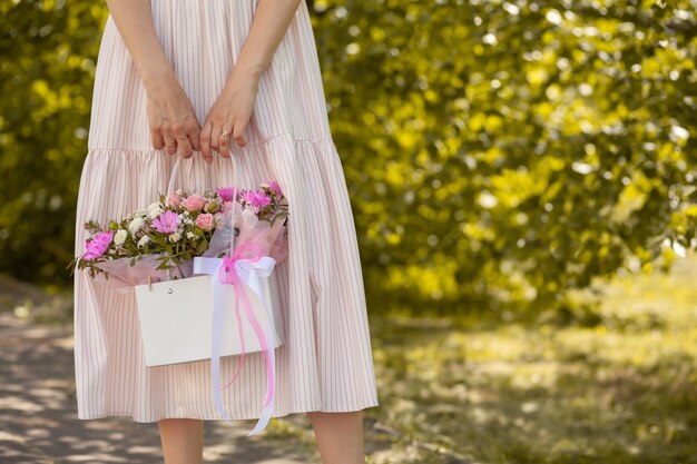 Un beau bouquet de fleurs dans une boîte entre les mains d'une belle fille qui marche le long de la rue