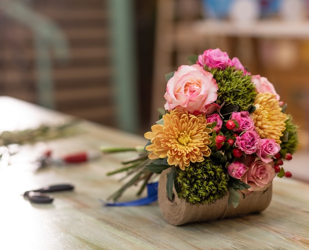 Photo beau bouquet de fleurs dans la table avec des équipements de fleuriste bouquet