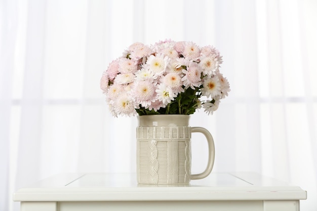 Beau bouquet de fleurs dans une tasse sur fond de fenêtre