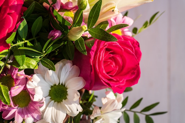 Beau bouquet de fleurs différentes dans une boîte sur fond en bois blanc.